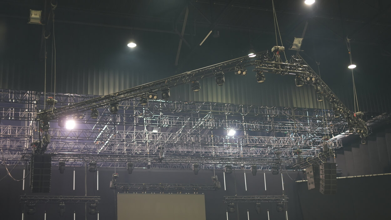 Pont lumière face en structure noire accroché en hauteur avec moteurs.