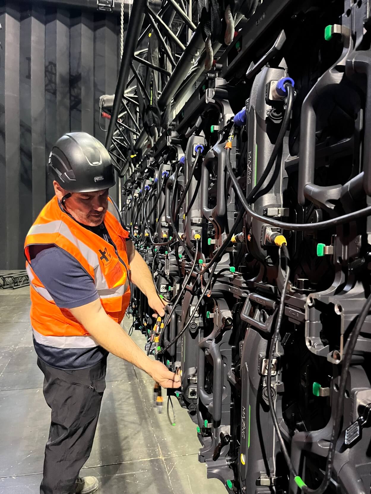 Technicien vidéo en train de finaliser le branchement d'un écran LED géant pour un festival dans le Grand-Est.